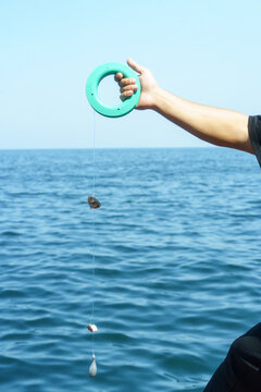 Handline fishing at sea with circular reel on a clear day. High resolution photo