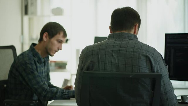 Two software engineers focus on programming and robotics arm, ensuring data integrity in a collaborative workspace.