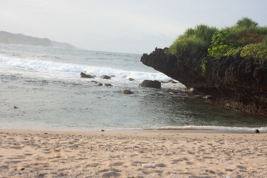 Coastal view with rocky formations and calm waves at dawn on the beach