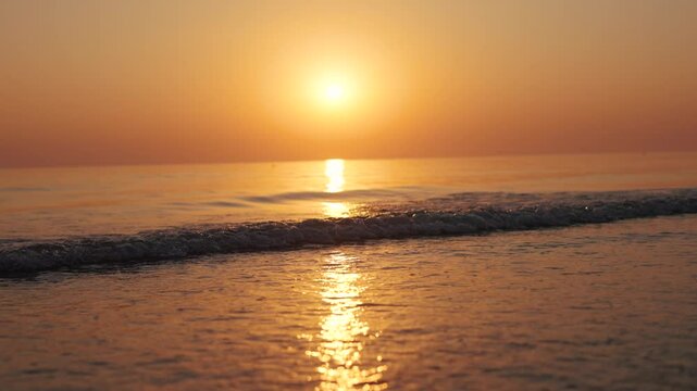4K Slow motion shot of a beautiful sunset at Mandvi Beach in Kutch, Gujarat, India. Sea waves and entire sea becomes golden in colour during the sunset. Orange colored sea. Natural sea background.