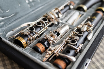 Obraz premium A black clarinet rests in an open case with a plush interior. The selective focus highlights its silver keys and sleek body, while the blurred background adds depth. 