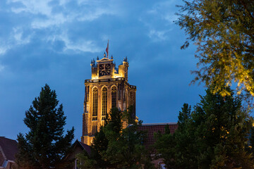 A majestic Gothic church under a dramatic cloudy sky. The intricate brickwork, towering windows,...