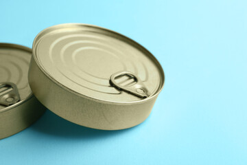 Tin cans with fish on blue background, closeup