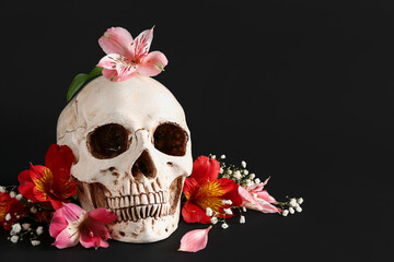 Human skull with beautiful lily and gypsophila flowers on black background
