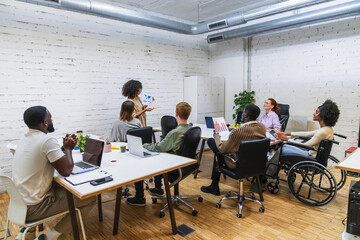 Diverse business team meeting in modern coworking space, discussing charts and strategies