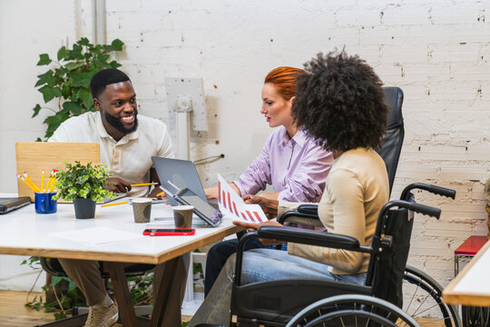 Diverse business team collaborating in coworking space with wheelchair user