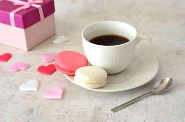 Coffee cup with saucer and Macarons and a gift box with silk hearts