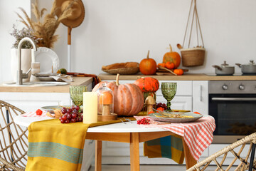 Autumn table setting with pumpkins and grapes in light kitchen