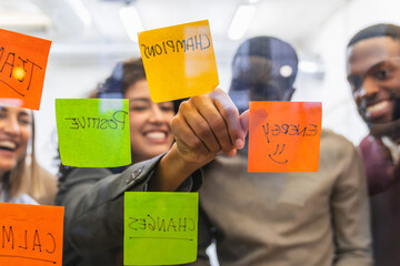 Coworkers brainstorming and sharing ideas using sticky notes on glass wall