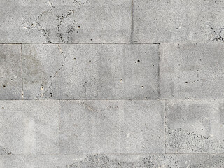 A wall made of grey stone facing slabs well fitted to each other. The texture of the stone is clearly visible