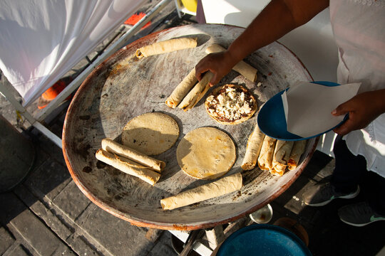 A woman cooking tortillas, flautillas and Mexican memelas on a comal on a street in Oaxaca.