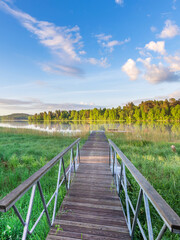 Fototapeta premium Wooden bridge over a lake with a clear blue sky above