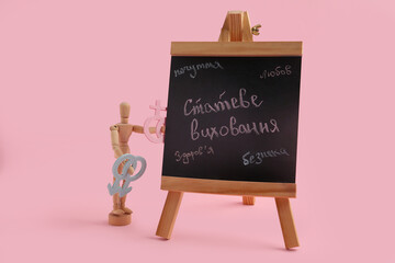 Chalkboard with written text in Ukrainian language, wooden mannequin, male and female symbols on...
