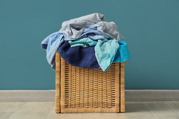 Laundry basket with dirty clothes near blue wall