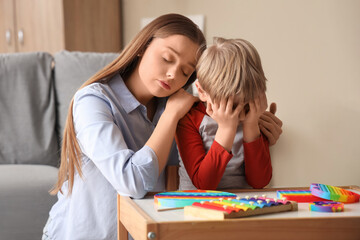 Female psychologist calming stressed little boy in office. World Autism Awareness Day