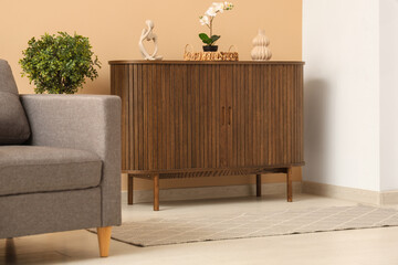 Wooden cabinet and grey armchair in interior of stylish living room