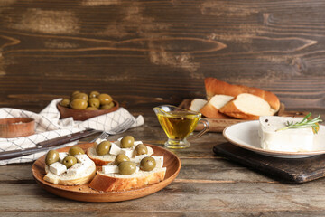 Plate of bread slices with tasty feta cheese and olives on wooden background
