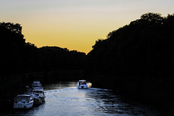 Fototapeta premium Boat cruising on a calm canal during sunset