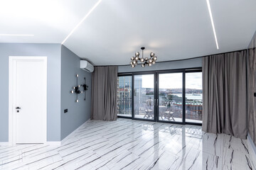 A large open living room with a white door and a window. The room is empty and has a modern feel