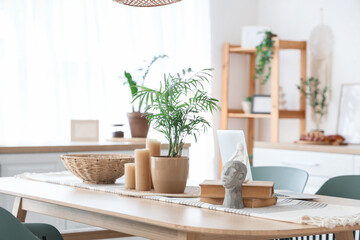 Houseplant, candles and statuette on table in dining room