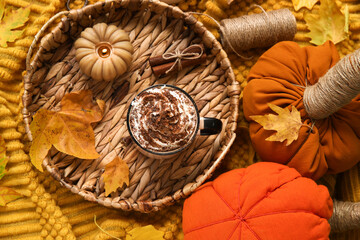 Autumn composition with cup of cocoa, leaves, candle and wicker tray on plaid as background