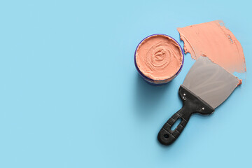 Knife with can of putty on blue background
