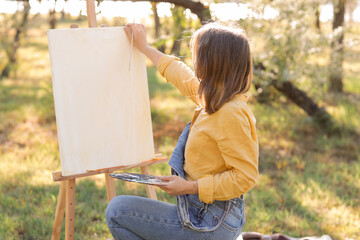 Female artist painting on canvas in park