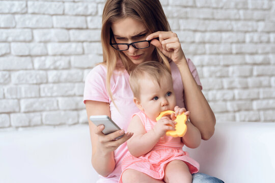 Young mother with little baby using smartphone. - Powered by Adobe