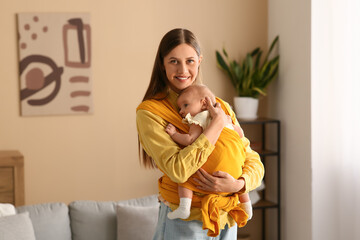 Young mother with little baby in sling  in living room