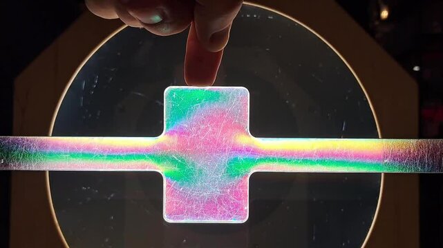 A polarized light experiment reveals stress patterns in a plastic sample. Scientific experiment.