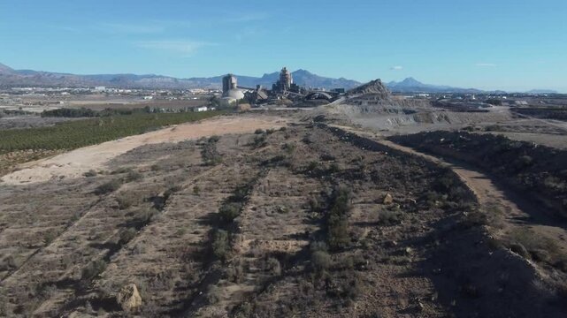 Aerial revealing a large cement factory. Dust in the air.