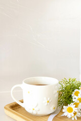 Cup of chamomile tea on a tray with chamomile flowers on a white background. Soothing and relaxing drink. Immunity. Cup of hot tea. Tea party concept. Tea ceremony.