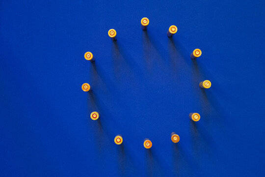 Circle of bullet casings on a blue background of the European Union's flag.  Metaphor of the European Union's growing focus on armament and defense,  in the context of geopolitical tensions. - Powered by Adobe