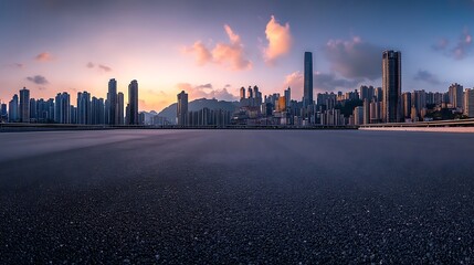 Fototapeta premium Panoramic city skyline at sunset, empty asphalt road in foreground.