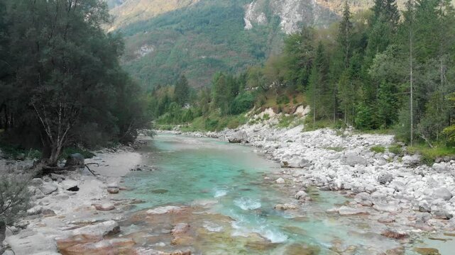 Drone flying above the Soča River near Trenta, rugged terrain and trees on sides