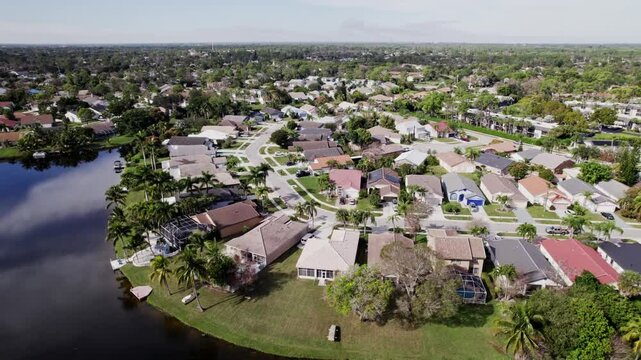 Aerial: West Palm Beach residential zone during the day with lagoon, crane down drone shot, USA