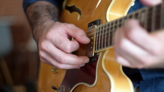Unique view of a guitarist playing complicated melodies notes in an expensive electric guitar