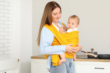 Young mother hugging little baby in sling at home