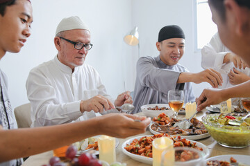 Grandfather And Grandson Enjoying Special Food Together Celebrating Eid At Dining Room