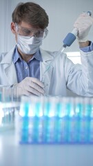 Male scientist researcher, wearing lab coat, white medical gloves, mask and protective glasses is...