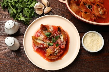 Delicious conchiglie pasta with ricotta cheese, tomato sauce and parsley on wooden table, flat lay