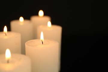 Many burning candles in darkness, closeup. Space for text