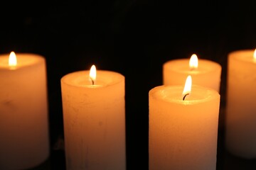 Many burning candles on black background, closeup