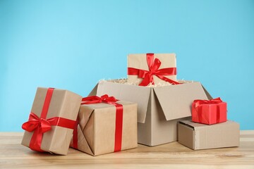 Parcel with gift boxes on wooden table against light blue background