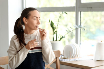 Beautiful woman taking pills at home
