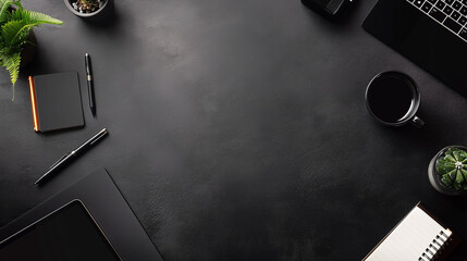 dark desktop with laptop and plants, pens, notebook and coffee cup