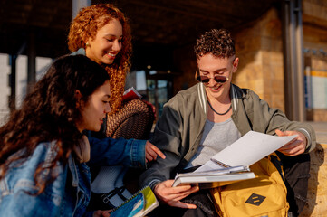 Obraz premium Smiling students sharing notes and studying together on university campus