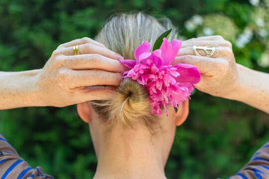 Blond woman fixing a flower in her bun.