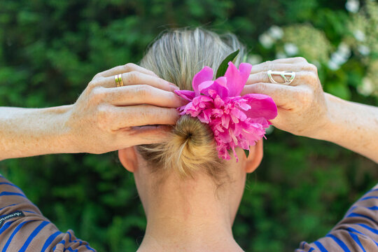 Blond woman fixing a flower in her bun.