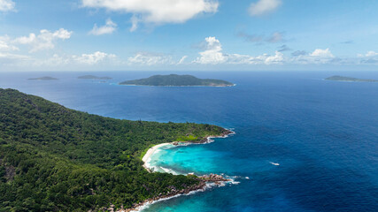 Tropical beach with turquoise waters, white sand, and surrounding greenery. Seychelles, La Digue.